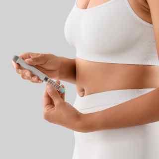Woman in white gym wear holding weight loss pen