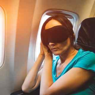 Woman putting on a face mask for sleep on a plane