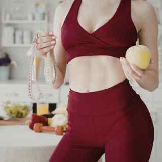 Woman after weight loss in gym gear with an apple