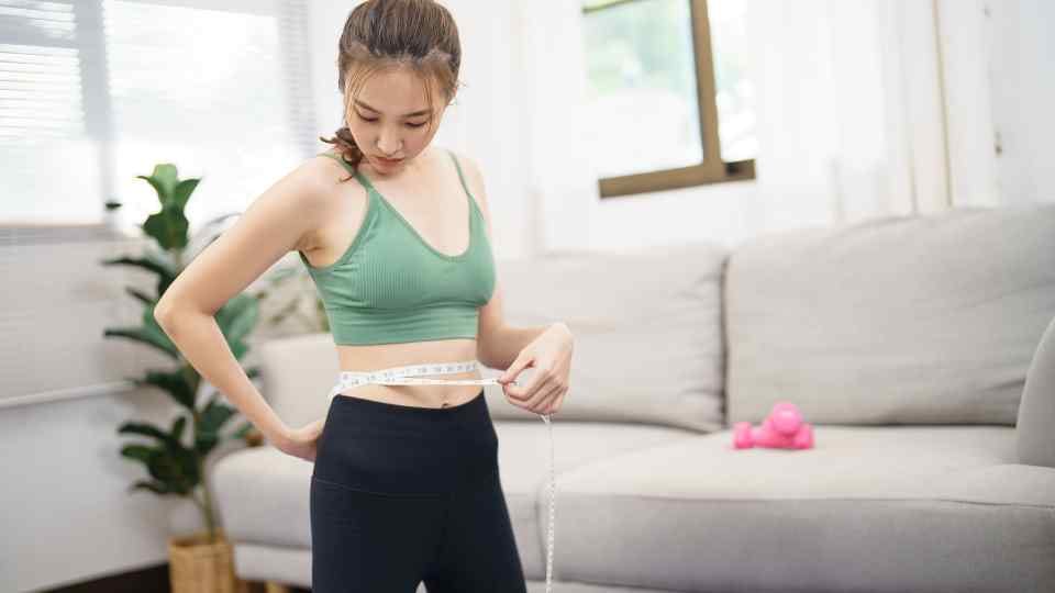 Woman measuring her waist for weight loss
